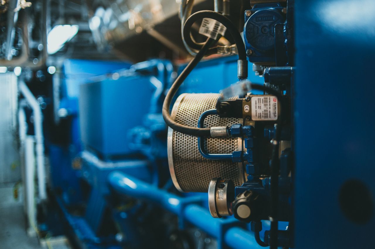 Close-up of an industrial machine with blue components and wires in a factory setting.